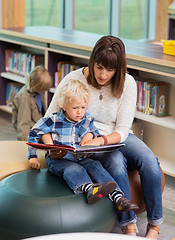 Image showing Teacher And Schoolboy Reading Book In Library