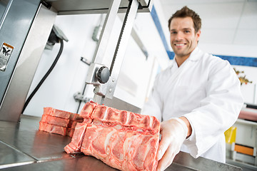 Image showing Male Butcher Cutting Meat On Bandsaw