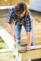 Image showing Worker Cutting Wood With Saw At Construction Site