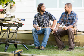 Image showing Carpenters Holding Disposable Coffee Cups On Wooden Frame At Sit