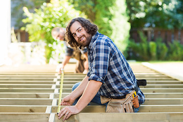 Image showing Portrait Of Carpenter Measuring Wood With Tape