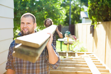 Image showing Carpenter And Coworker Carrying Lumbers At Construction Site