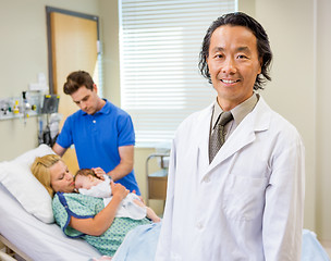 Image showing Mature Doctor Standing With Couple And Newborn Baby In Backgroun