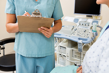 Image showing Nurse Writing On Clipboard With Patient In Ultrasound Room