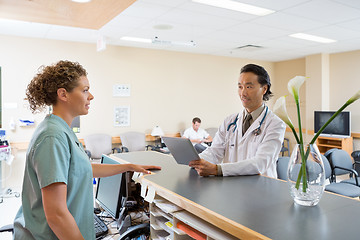 Image showing Nurse And Doctor Conversing At Hospital Reception