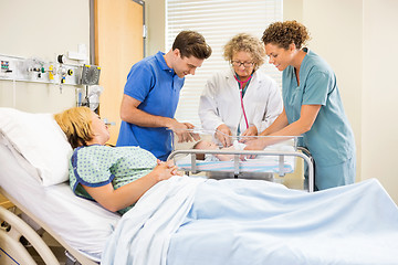 Image showing Doctor Examining Baby While Parents And Nurse Looking At Her