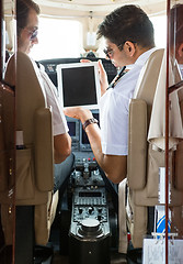 Image showing Pilot Showing Digital Tablet To Copilot In Cockpit