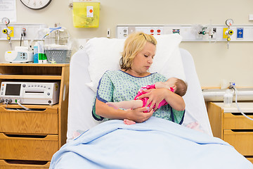 Image showing Mother Looking At Newborn Baby Girl While Sitting On Bed