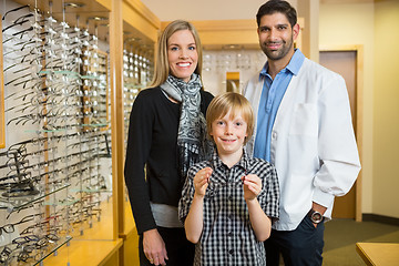 Image showing Boy Holding Glasses With Mother And Optician In Store