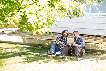 Image showing Workers With Mobilephone And Digital Tablet Leaning On Wooden Fr