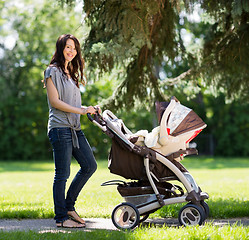 Image showing Beautiful Woman Pushing Baby Carriage In Park