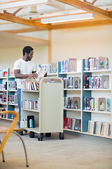 Image showing Librarian With Trolley Arranging Books In Library