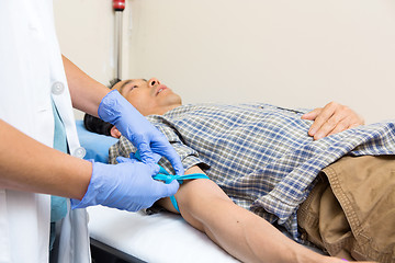 Image showing Nurse Tying Strap On Patient's Arm Before Blood Collection