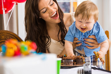 Image showing Mother Holding Boy With Messy Hands Covered With Cake Icing