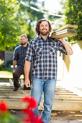 Image showing Carpenter And Coworker Carrying Wooden Planks At Construction Si