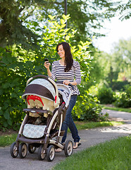 Image showing Woman With Baby Carriage Using Cell Phone In Park