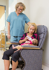 Image showing Nurse Looking At Woman Feeding Newborn Babygirl On Chair