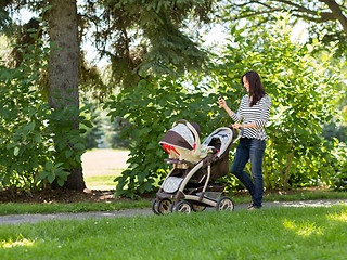 Image showing Woman With Baby Carriage Using Cell Phone In Park