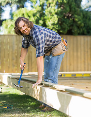 Image showing Manual Worker Hammering Nail Into Wood At Site