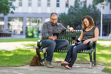 Image showing Students Using Digital Tablet On Bench At Campus