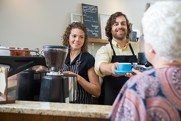 Image showing Cafe Owners Serving Coffee To Woman At Counter