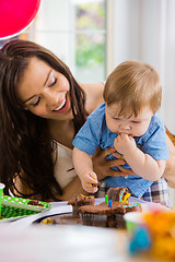 Image showing Mother Looking At Baby Boy Eating Cupcake