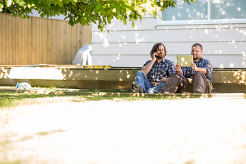 Image showing Worker Using Digital Tablet While Coworker On Call At Site