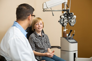 Image showing Boy Smiling While Sitting With Optometrist In Store