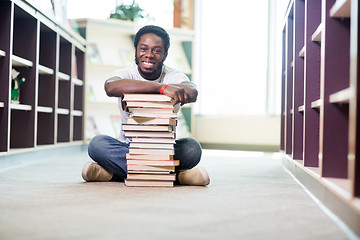 Image showing Confident Student With Stacked Books Sitting In Library