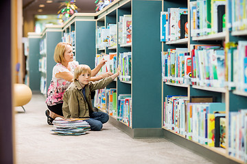 Image showing Boy With Teacher Selecting Books From Bookshelf