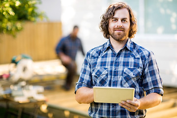 Image showing Manual Worker Holding Digital Tablet With Coworker Working In Ba