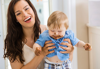 Image showing Mother Holding Baby Boy With Cake Icing On Face