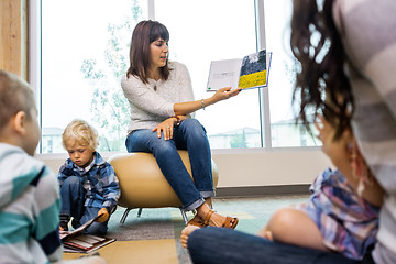 Image showing Teacher Reading Book To Students In Library