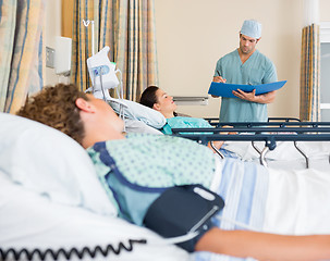 Image showing Patient's Lying On Bed While Nurse Examins Report