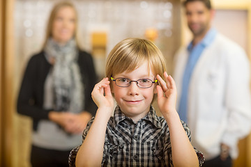 Image showing Boy Trying Glasses With Optometrist And Mother At Store
