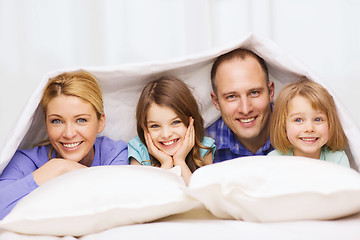 Image showing happy family with two kids under blanket at home