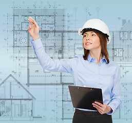 Image showing smiling businesswoman in helmet with clipboard