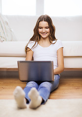 Image showing smiling teenage girl with laptop computer at home