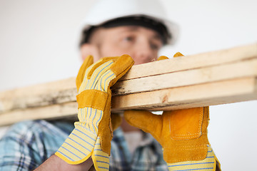 Image showing close up of male in gloves carrying wooden boards