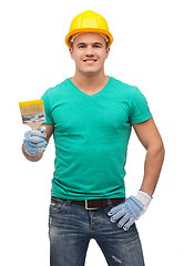 Image showing smiling manual worker in helmet with paintbrush