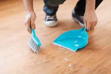 Image showing close up of male brooming wooden floor