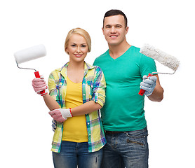 Image showing smiling couple in gloves with paint rollers