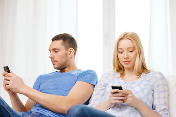 Image showing concentrated couple with smartphones at home