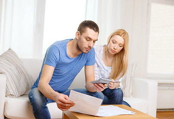 Image showing busy couple with papers and calculator at home