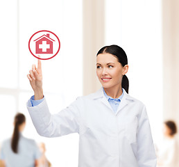 Image showing smiling female doctor pointing to hospital sign