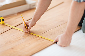 Image showing close up of male hands measuring wood flooring