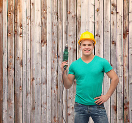 Image showing smiling manual worker in helmet with drill machine