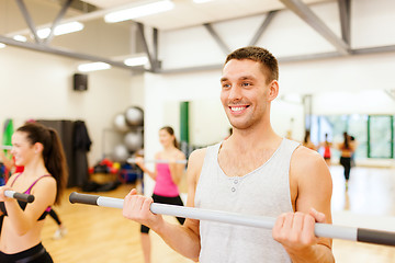 Image showing group of smiling people working out with barbells