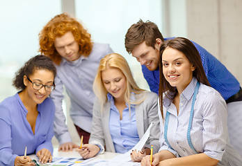 Image showing smiling creative team looking over clothes designs