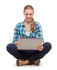 Image showing smiling woman with laptop sitting on floor
